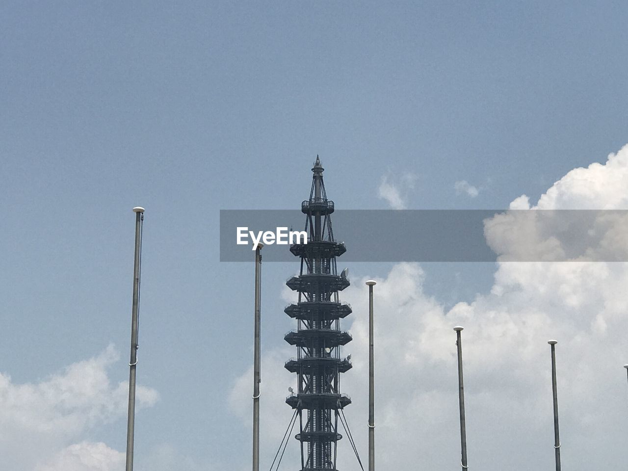 LOW ANGLE VIEW OF COMMUNICATIONS TOWER BY BUILDING AGAINST SKY