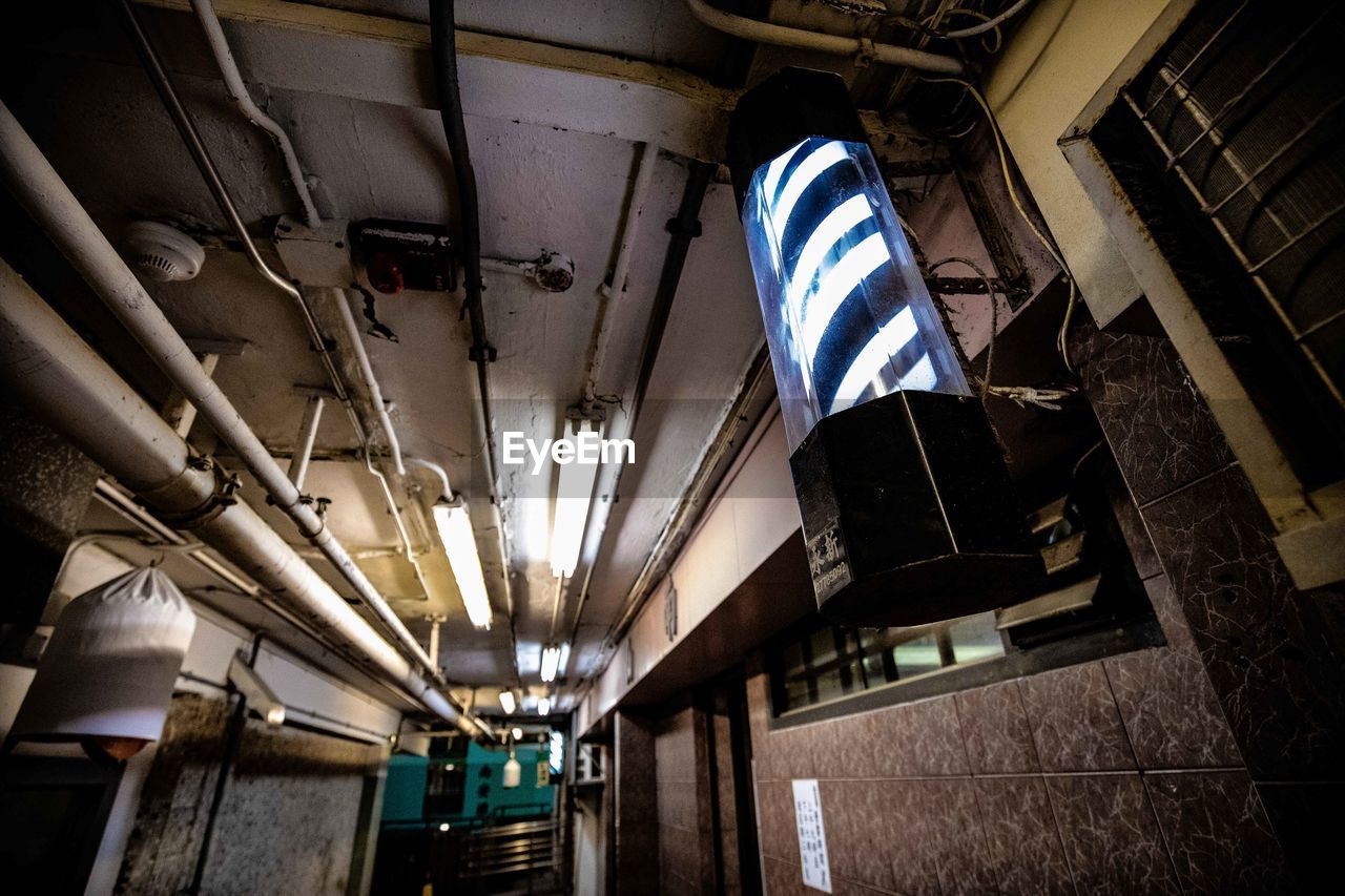 LOW ANGLE VIEW OF ILLUMINATED LIGHTING EQUIPMENT HANGING AT NIGHT