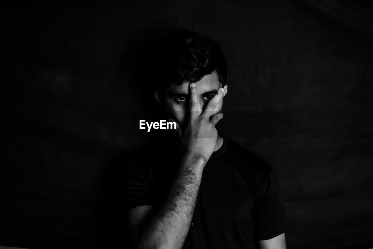 Portrait of young man against black background