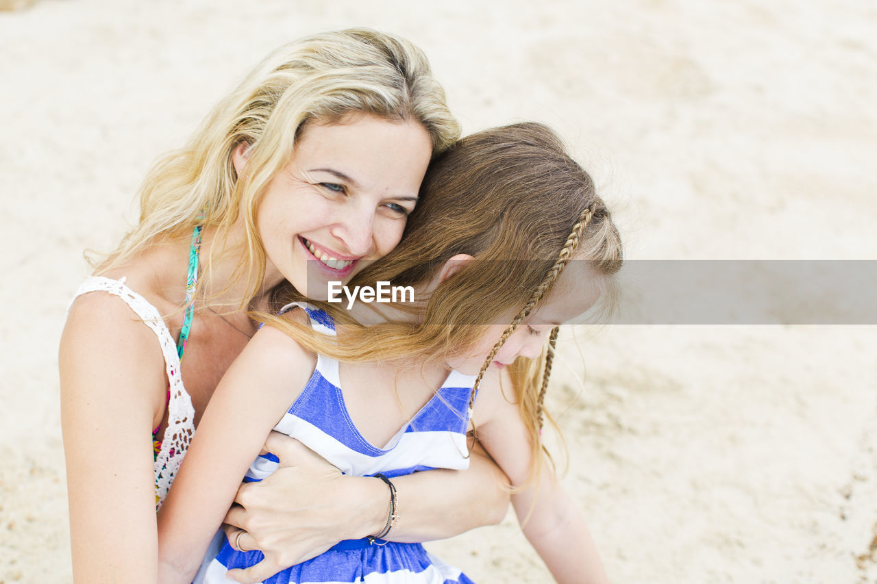 Smiling mother with daughter at beach