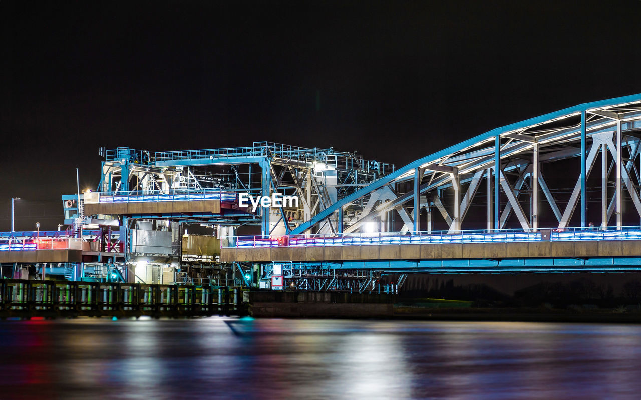 Illuminated bridge over river at night