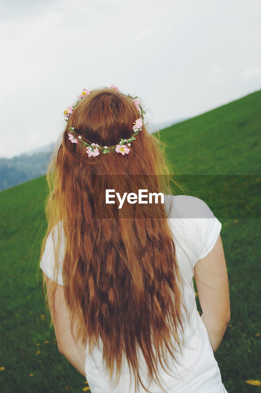 Rear view of redhead teenage girl standing outdoors