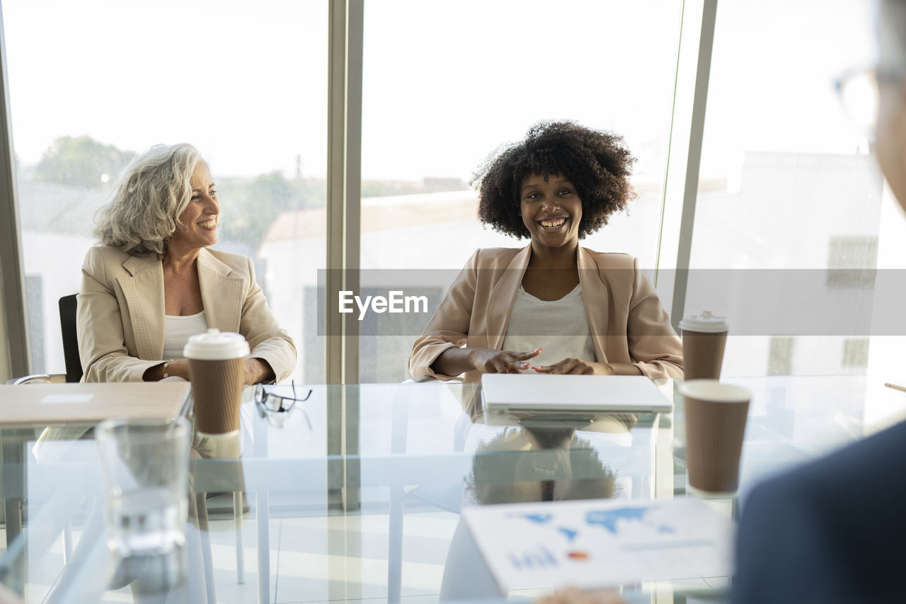 Senior businesswoman looking at colleague discussing in meeting at office