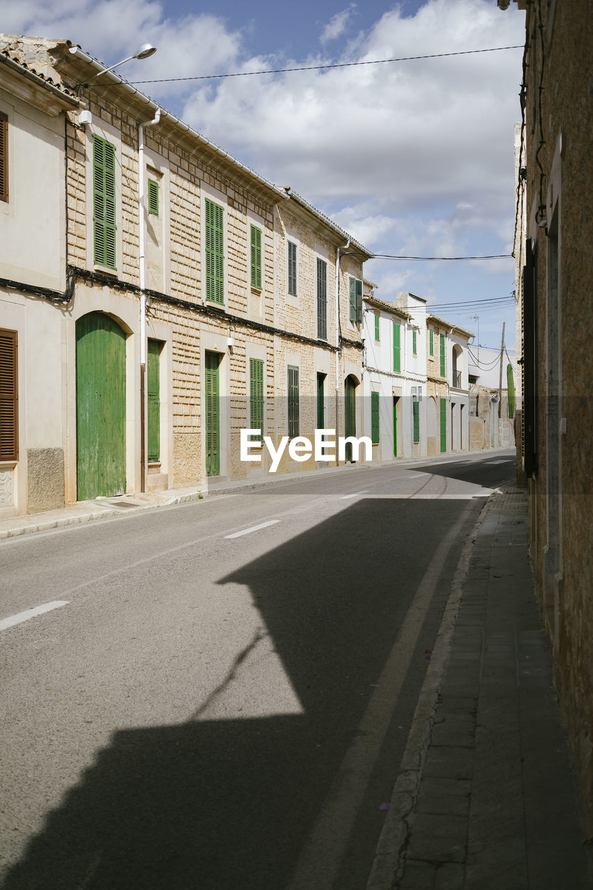 EMPTY ROAD AMIDST BUILDINGS IN CITY