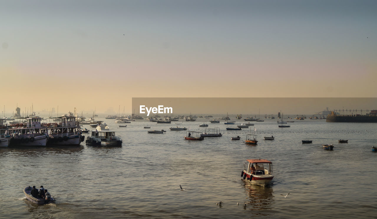 Boats sailing in sea against clear sky