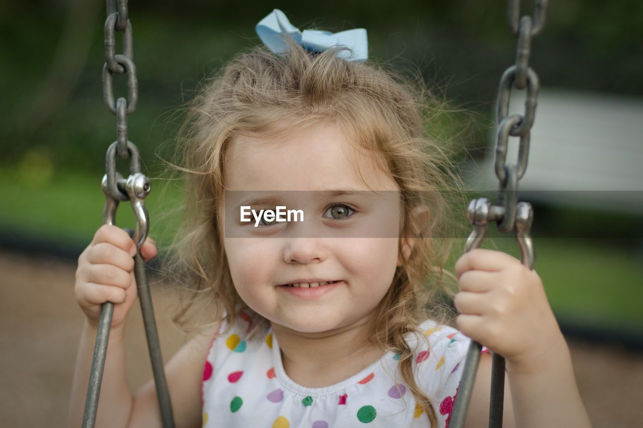 Portrait of smiling girl sitting on swing