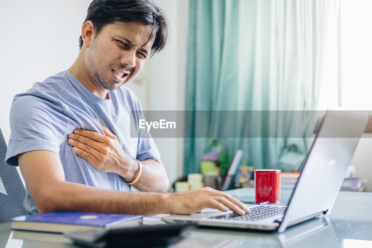 MIDSECTION OF MAN WORKING WITH LAPTOP