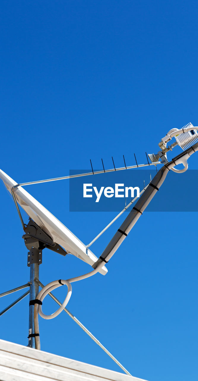 LOW ANGLE VIEW OF POWER LINES AGAINST CLEAR BLUE SKY