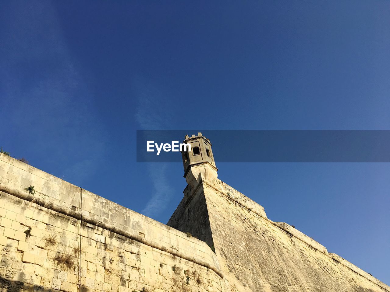 Low angle view of lookout tower on fort at floriana against blue sky