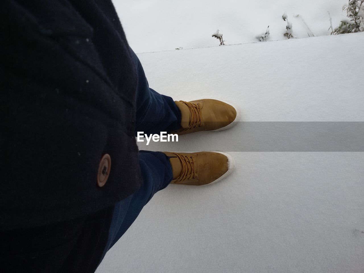 LOW SECTION OF MAN WITH SNOW ON SNOWY LANDSCAPE