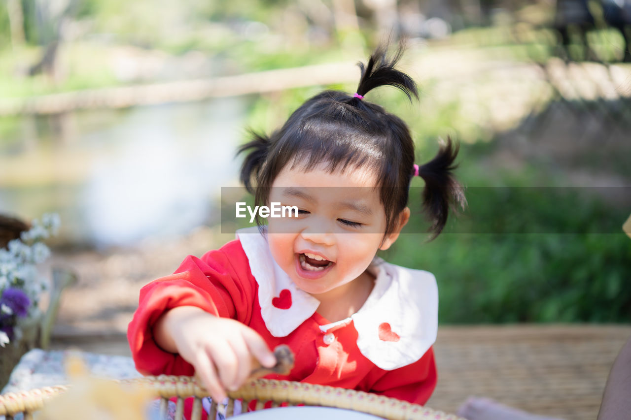 Cute girl holding food while sitting at park