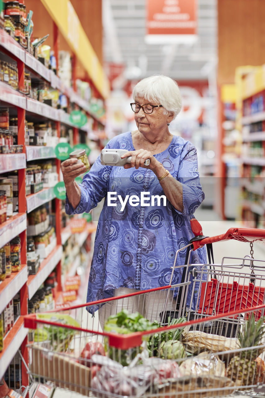 Senior woman using barcode reader in shop