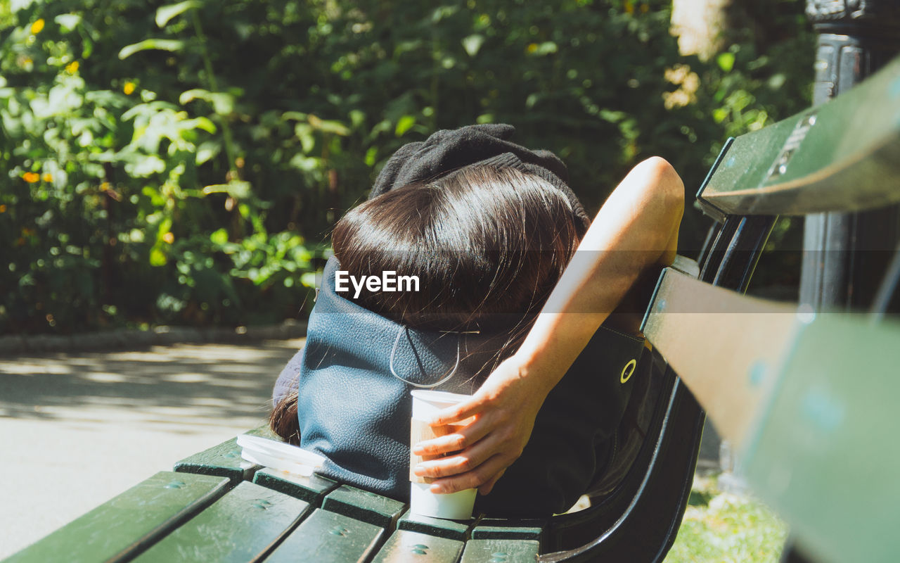 Woman sleeping on bench at park