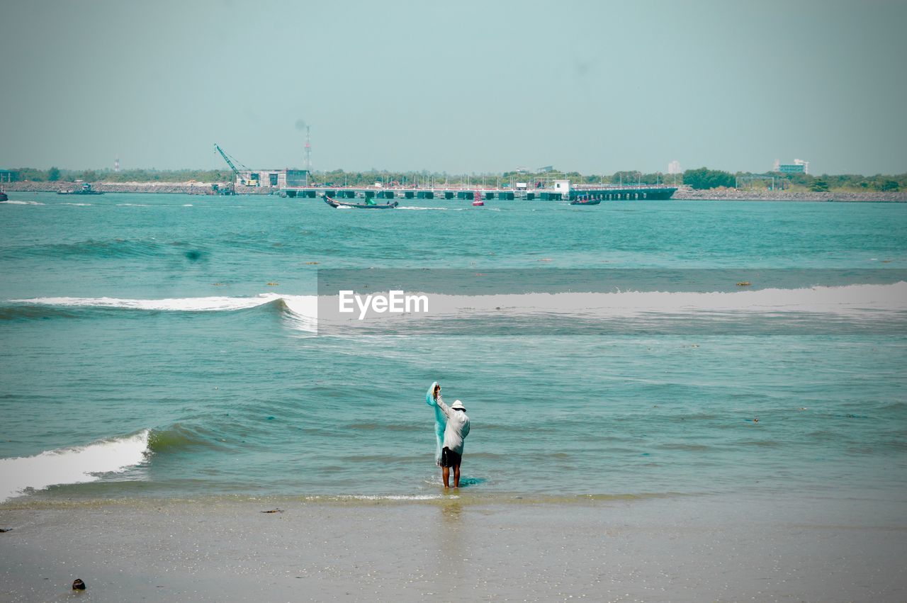 REAR VIEW OF MAN ON BEACH