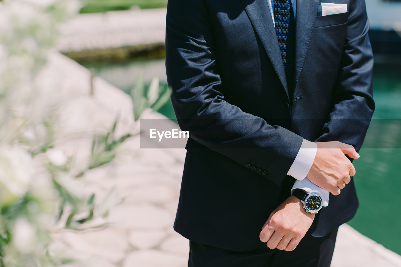 Midsection of man wearing suit during sunny day