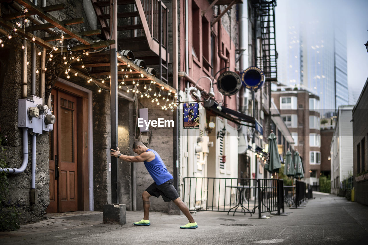 Side view of man exercising by pole on street