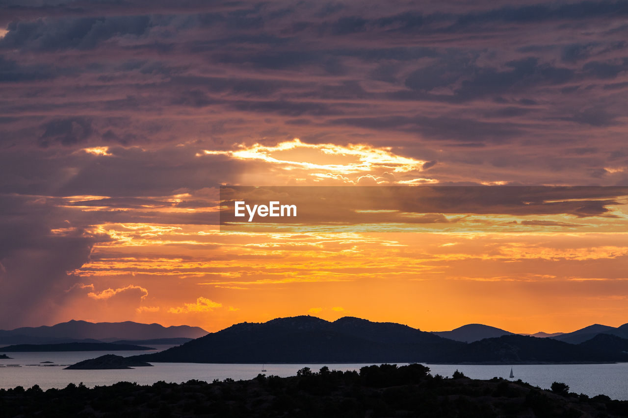 Scenic view of silhouette mountains against orange sky, murter, croatia