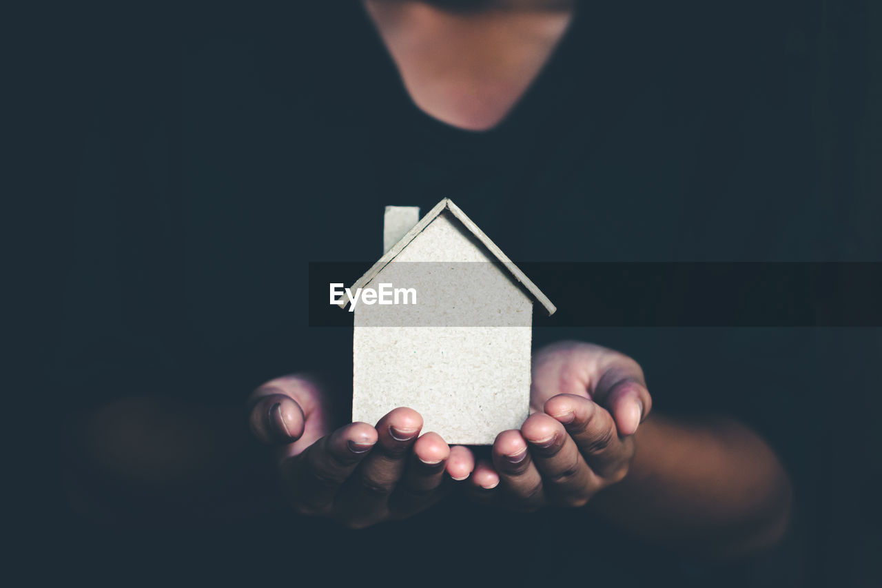 Midsection of man holding model home