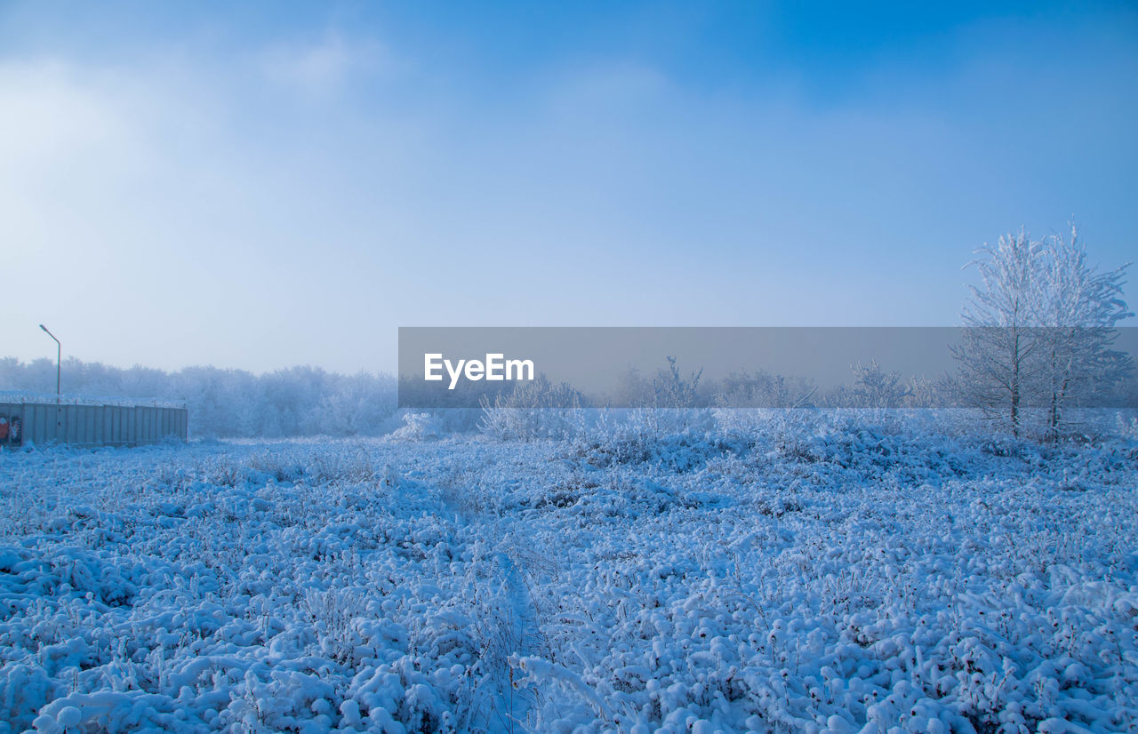 SNOW COVERED LAND AGAINST BLUE SKY