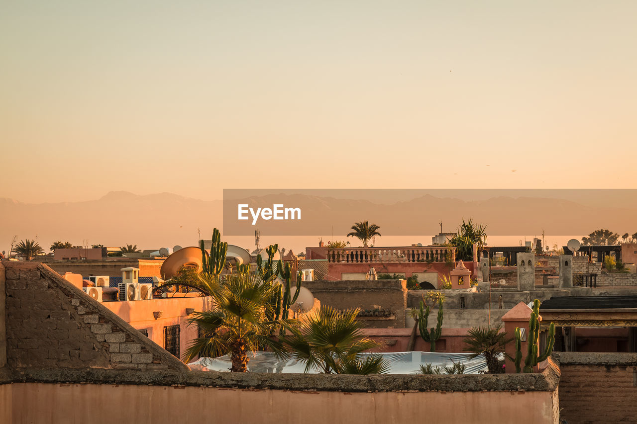 Buildings in town against clear sky during sunset