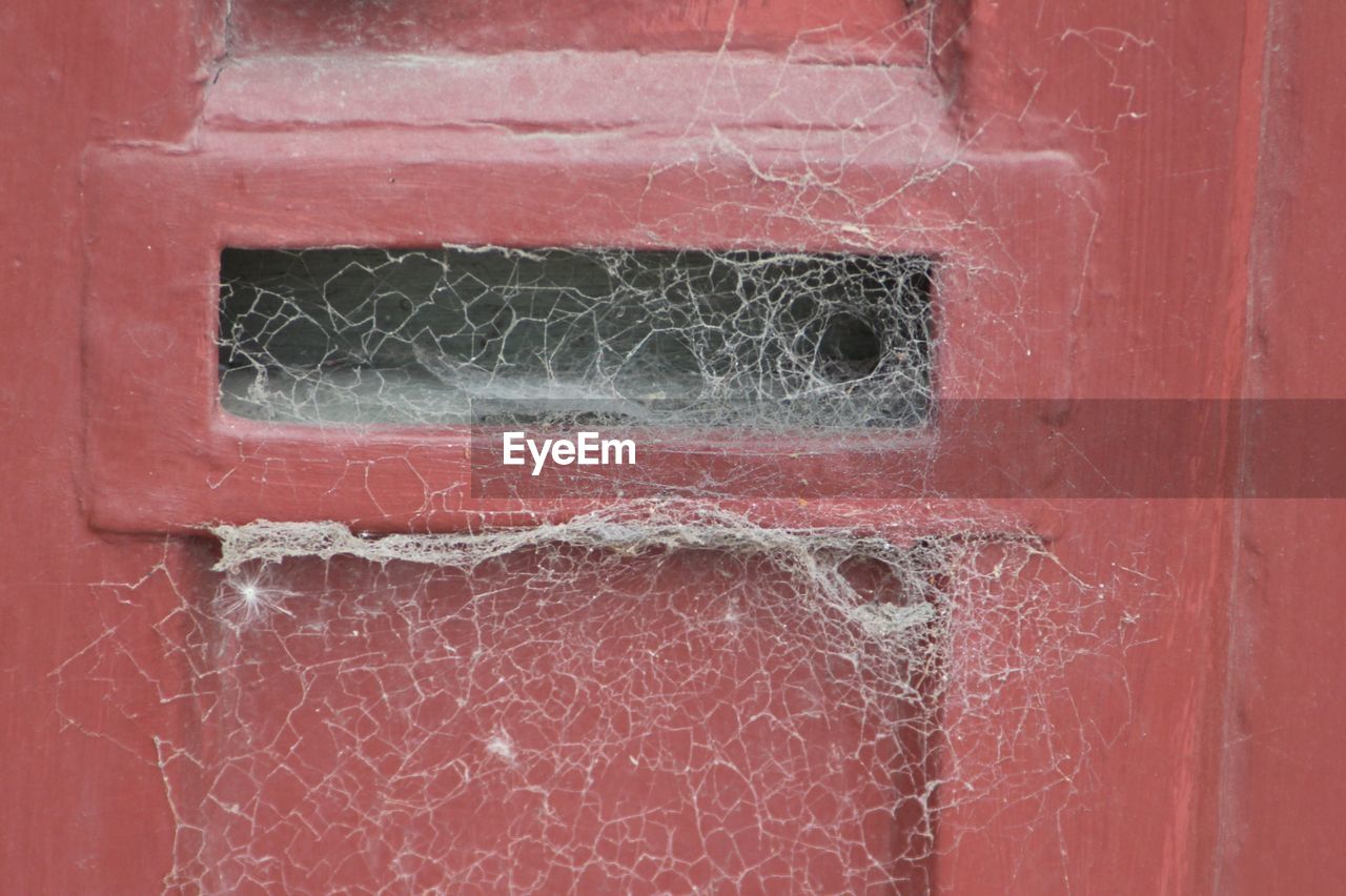 Close-up of spider web on red metallic mailbox