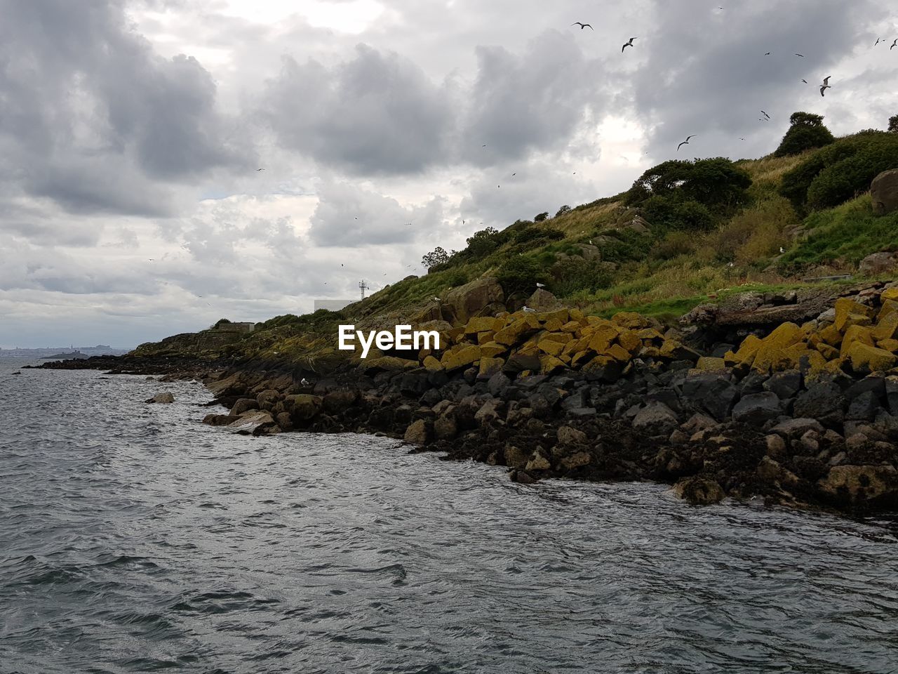 ROCKS BY SEA AGAINST SKY