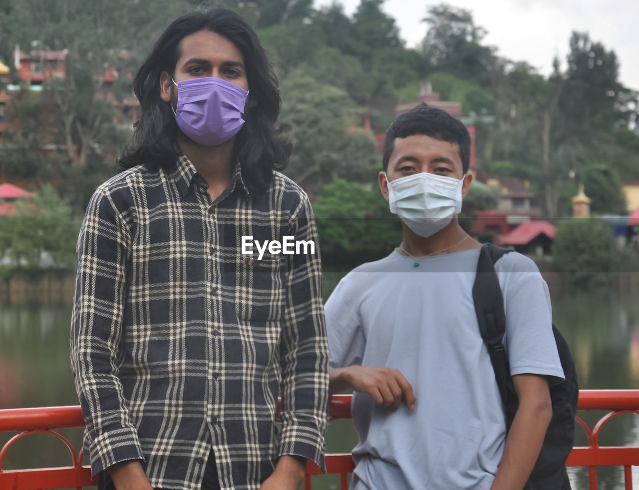 Two male friends with wearing face mask standing outside with looking at camera