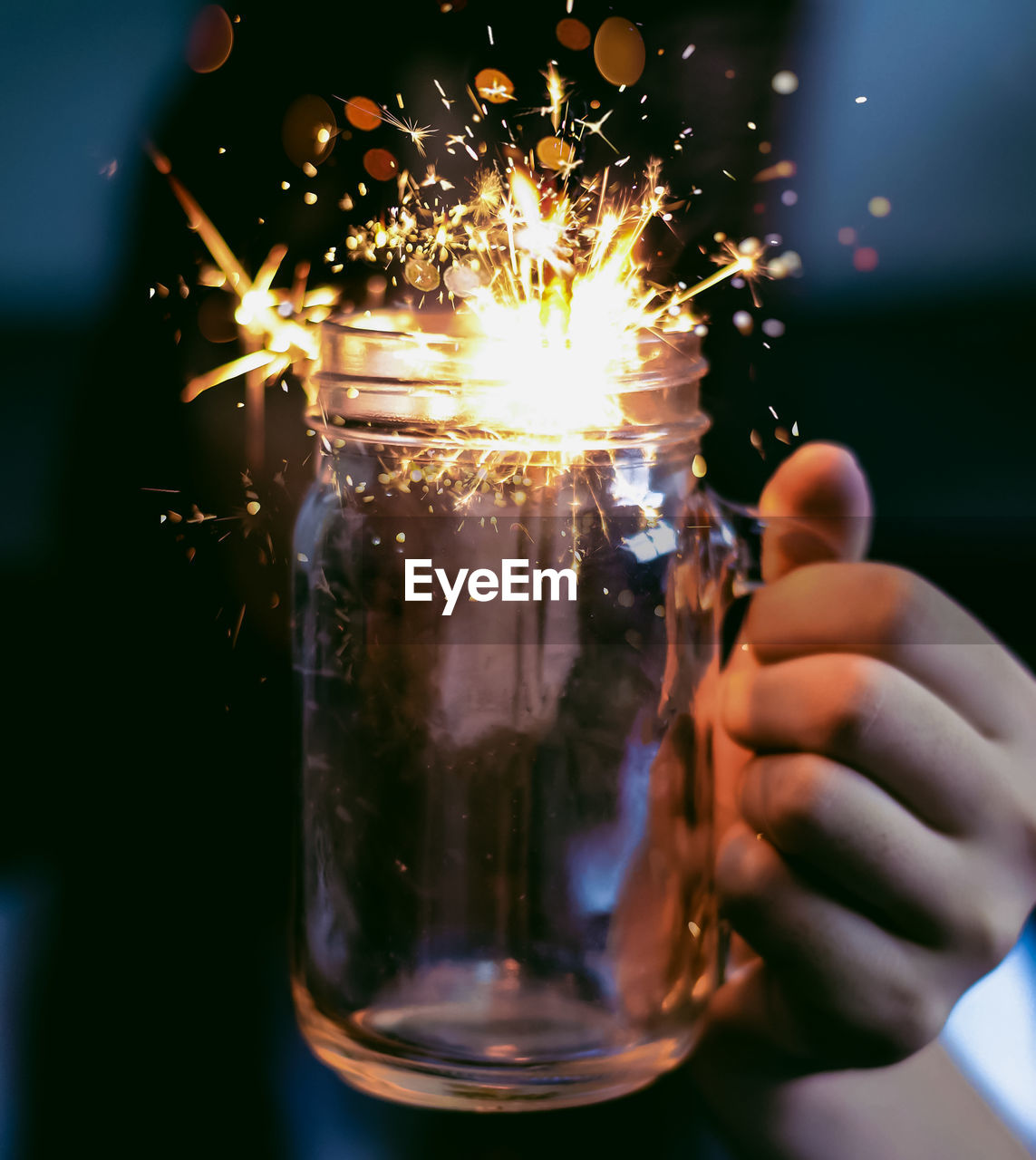 Close-up of hand holding sparkler in jar