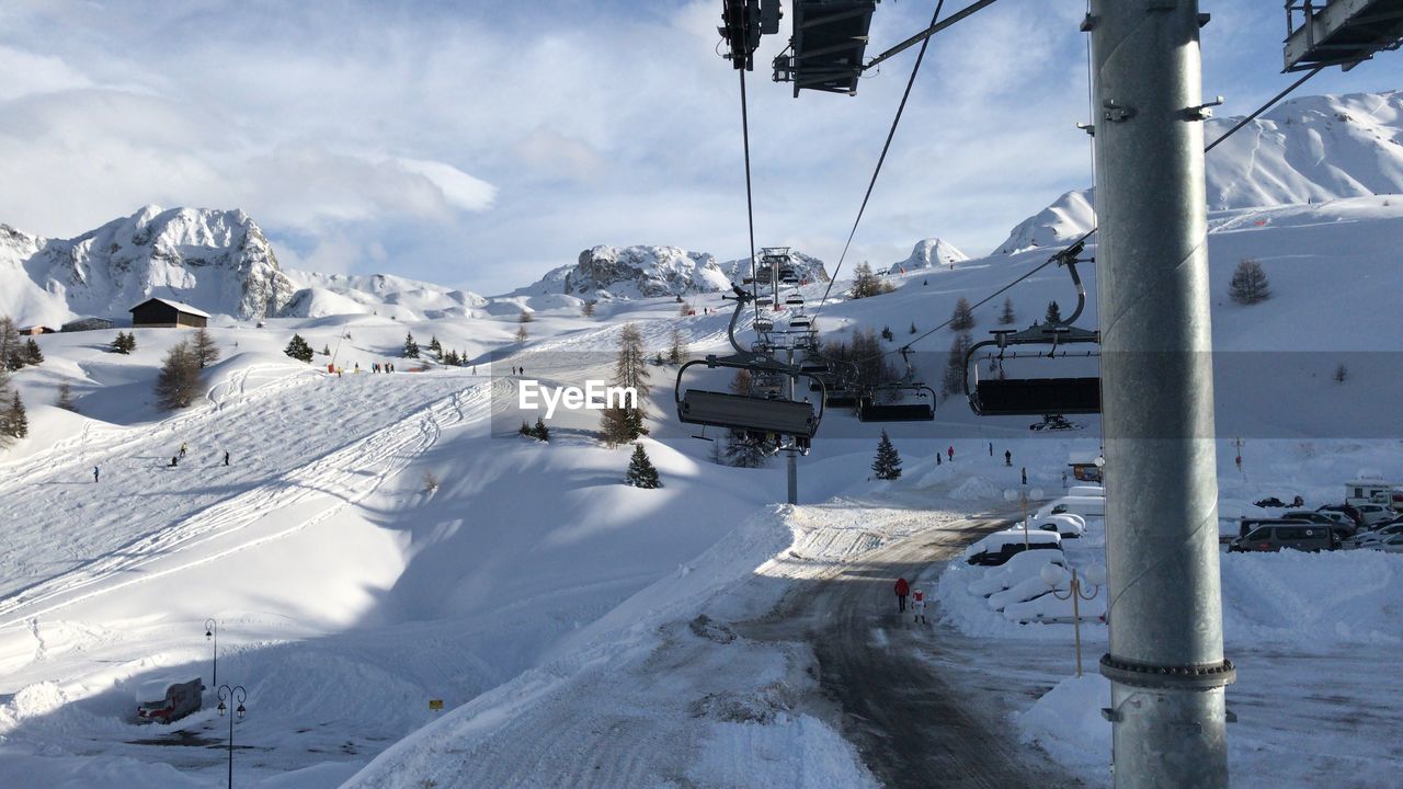 View of ski lift over snowcapped mountains against sky