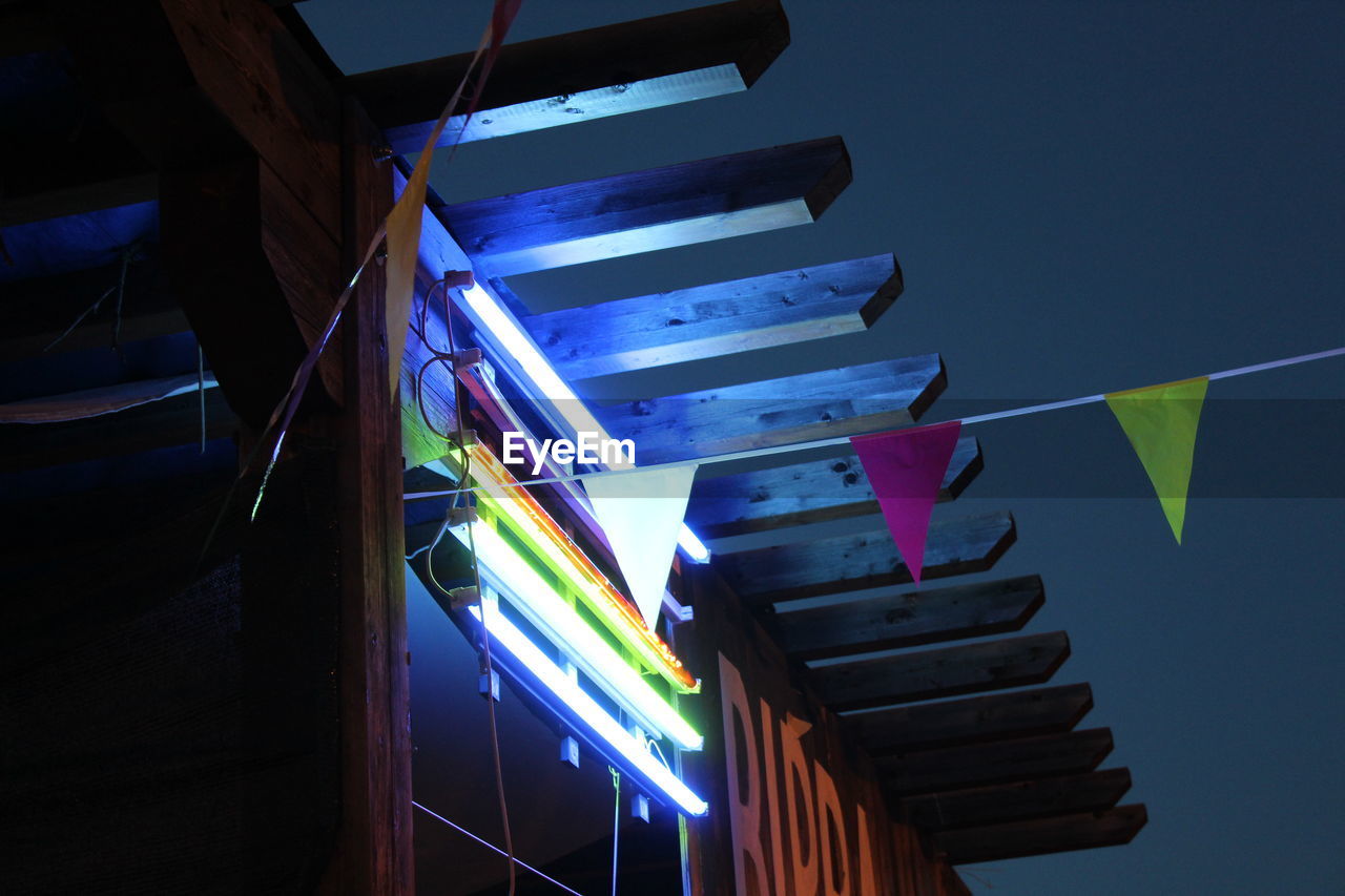 LOW ANGLE VIEW OF ILLUMINATED LIGHTING EQUIPMENT AGAINST CLEAR SKY