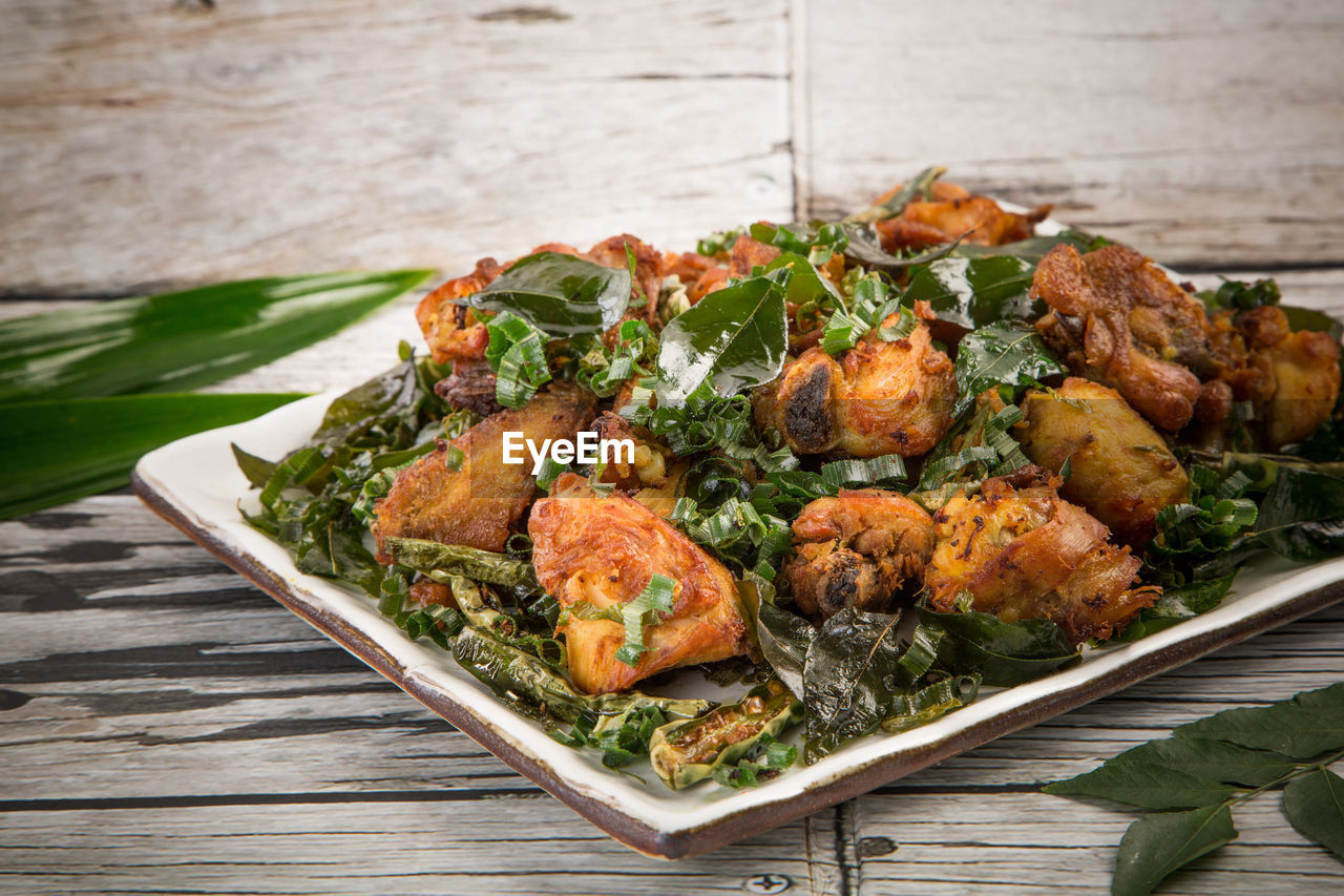 Close-up of chicken meat served in plate on wooden table