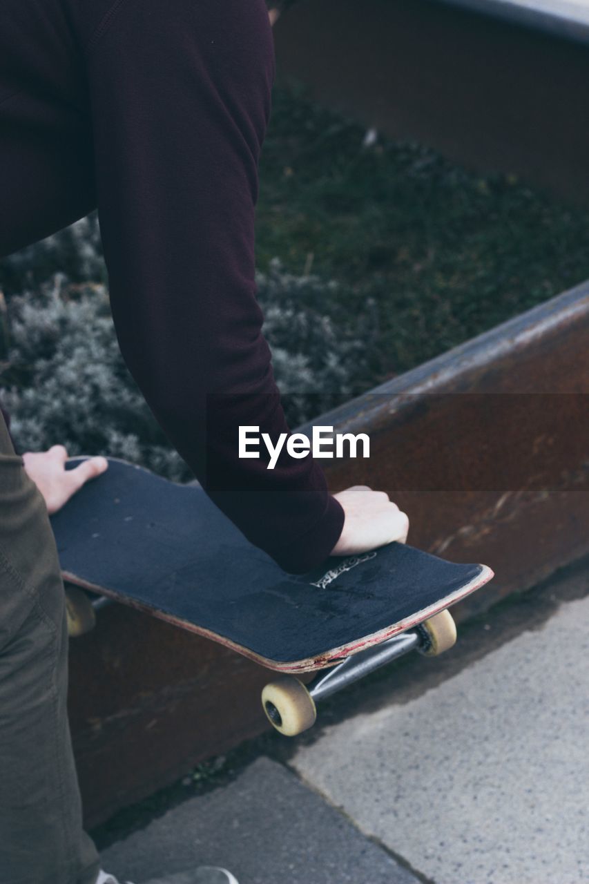 Midsection of man holding skateboard