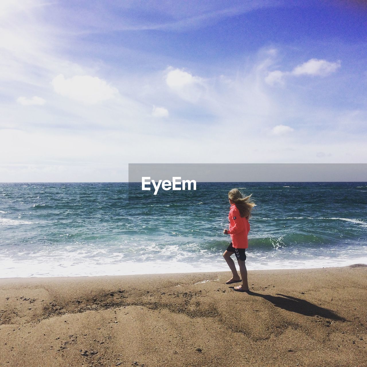 Full length of girl walking at beach against sky