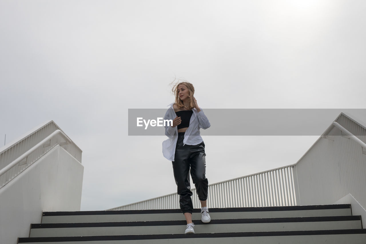 Low angle view of woman on staircase against building