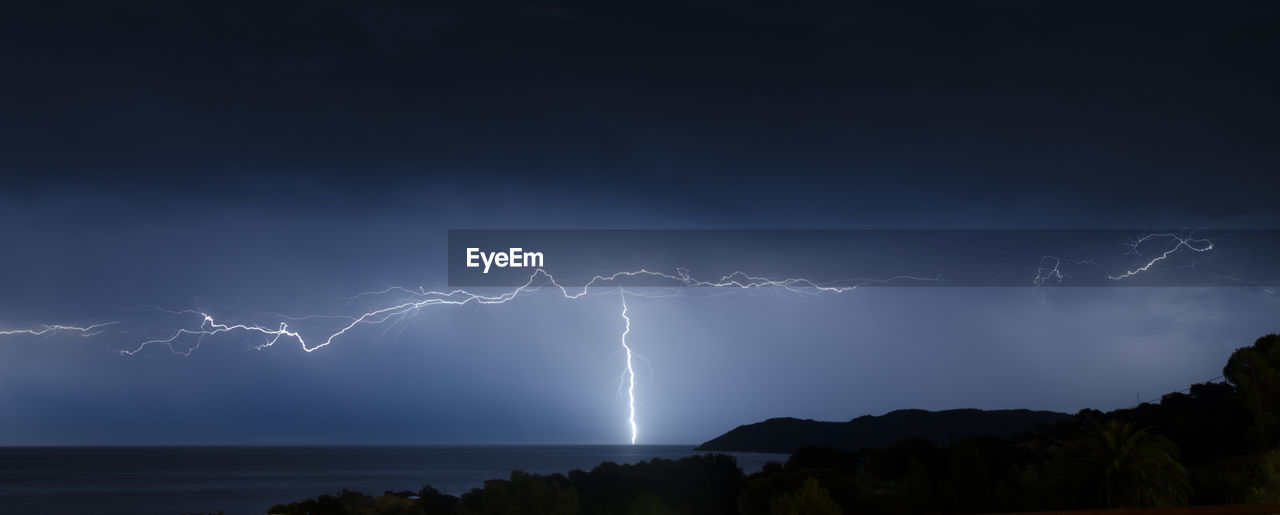 Scenic view of lightning over sea at night