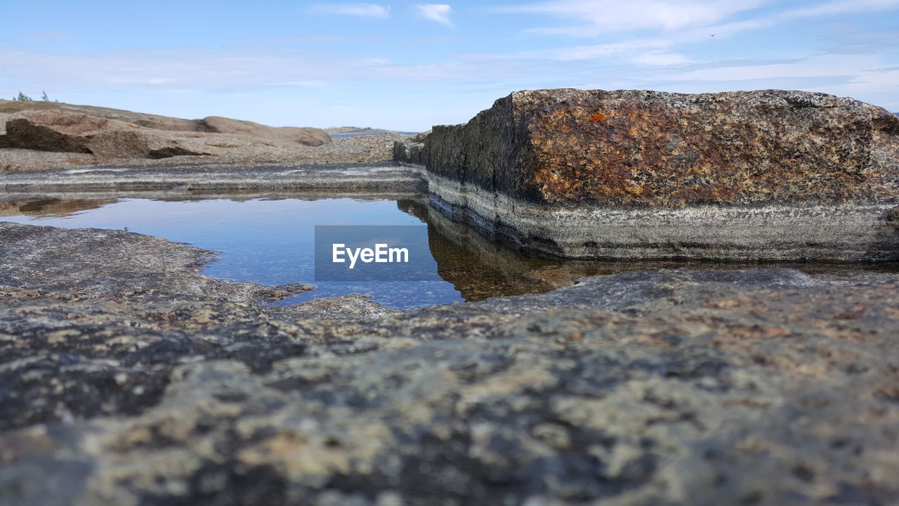 Surface level of rocks on beach against sky