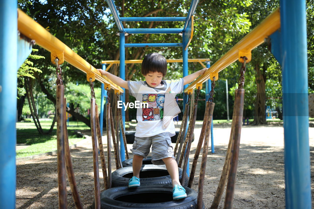 FULL LENGTH OF BOY ON SWING AT PLAYGROUND