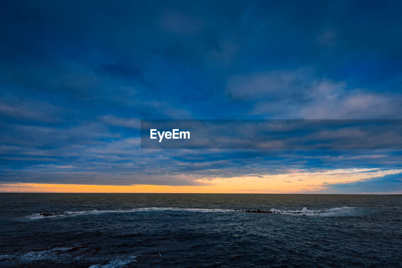 Sunset over the sea with cloudy sky and sun glow in the background