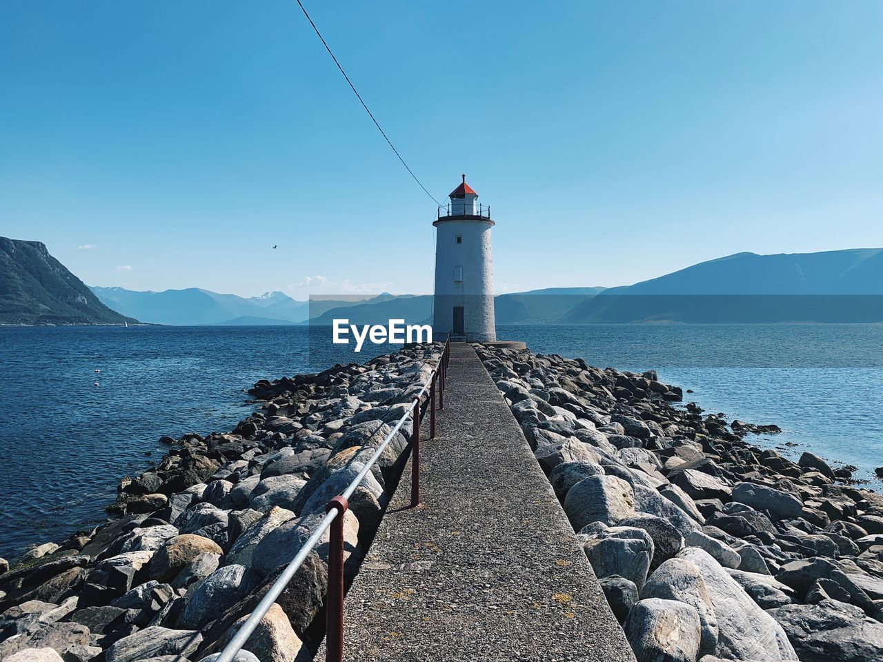 Lighthouse by sea against blue sky in a wilderness environment with copy space 