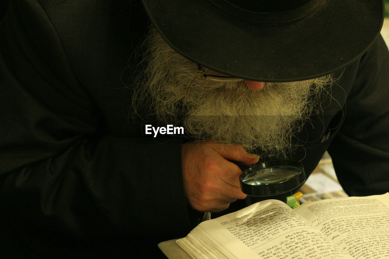 Detective reading book through magnifying glass