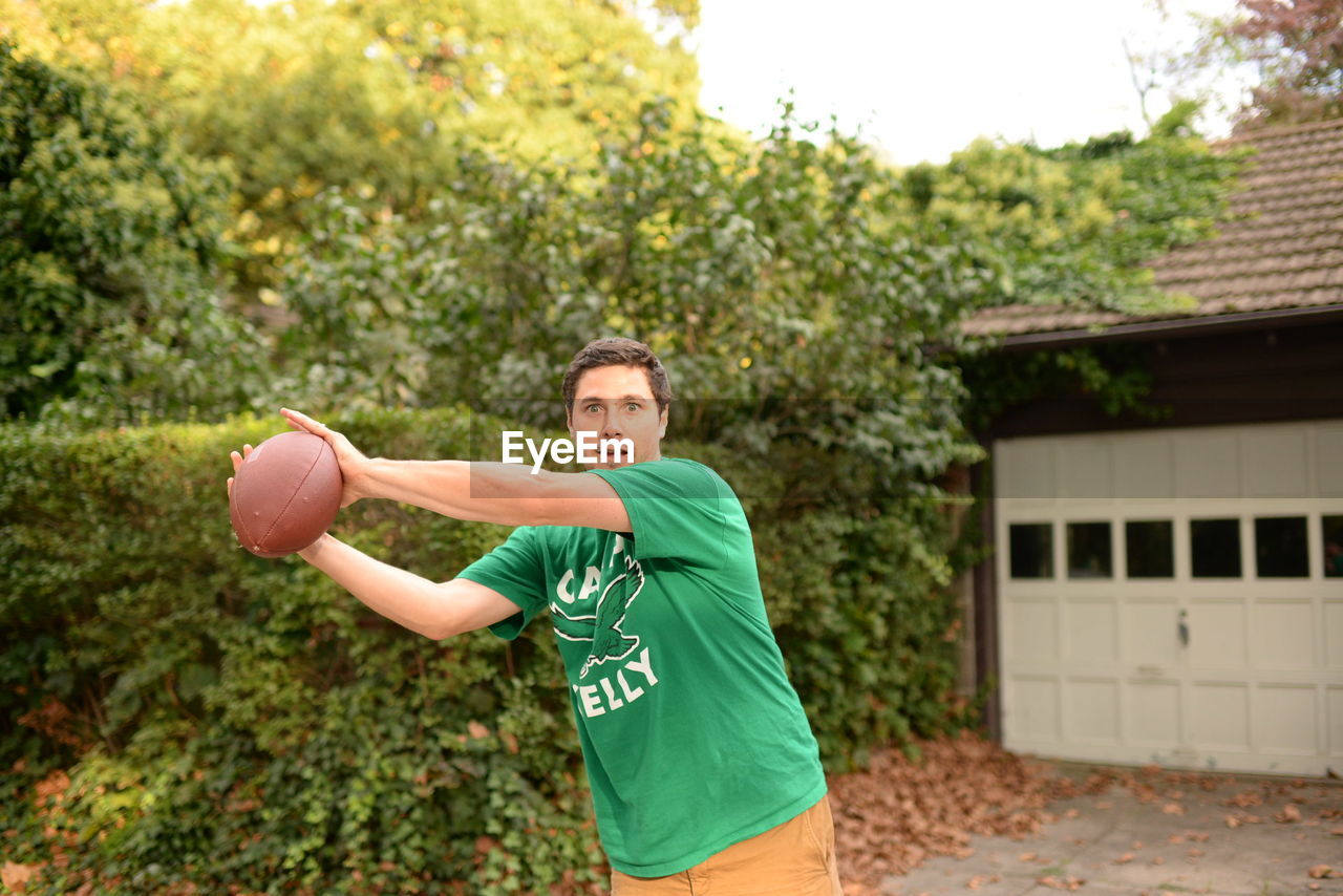 Man holding ball in yard against clear sky