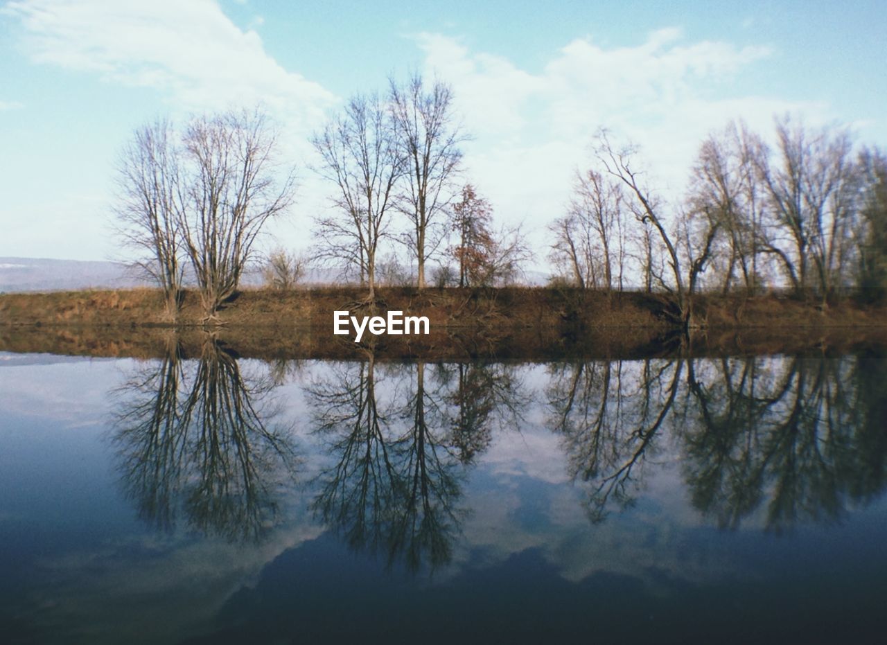 Tranquil scene of bare trees against sky reflected in lake water