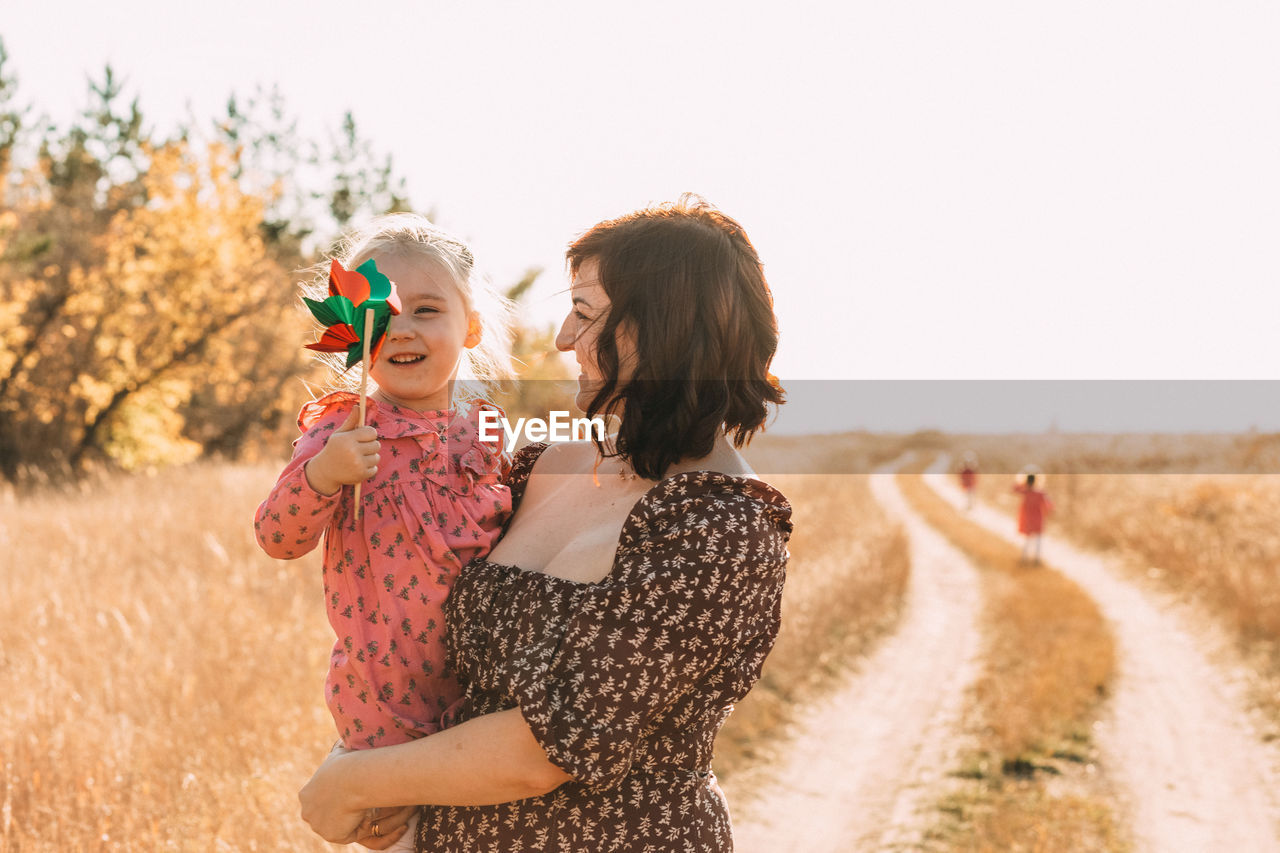 Mom shows little daughter how to use a windmill on outdoor. esg and clean energy concept.