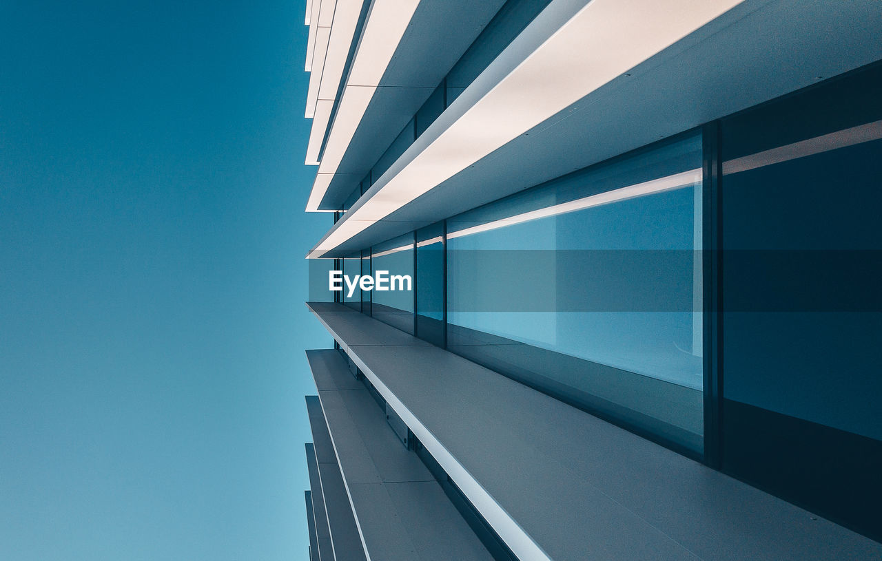 Low angle view of modern building against clear blue sky