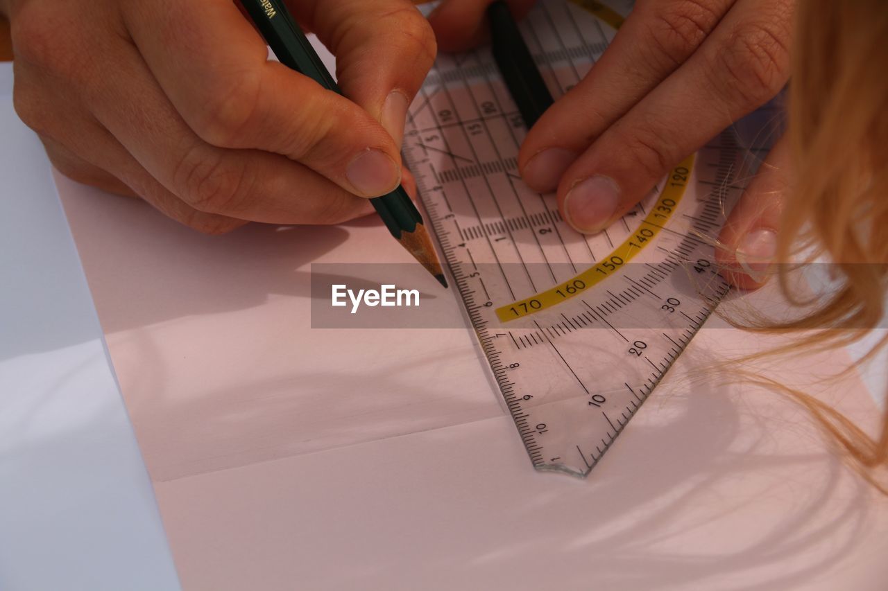 Close-up of woman drawing using ruler on paper