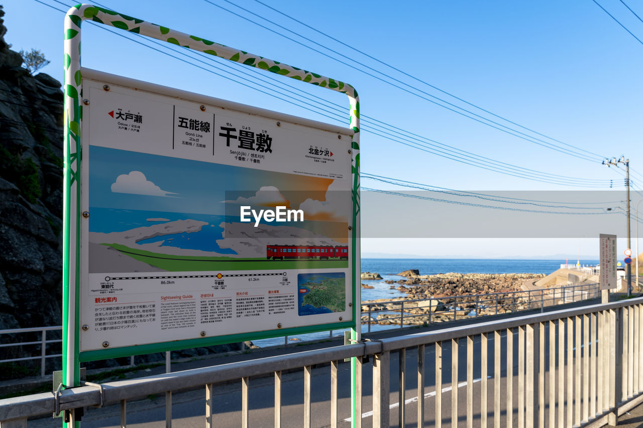 INFORMATION SIGN BY RAILING AGAINST SEA