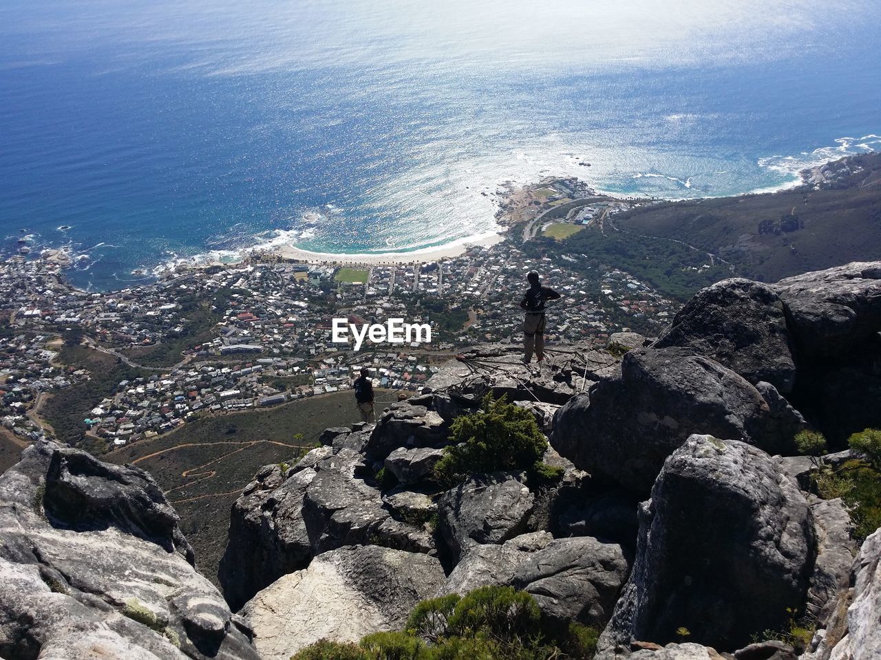 Aerial view of people standing at table mountain against sea on sunny day
