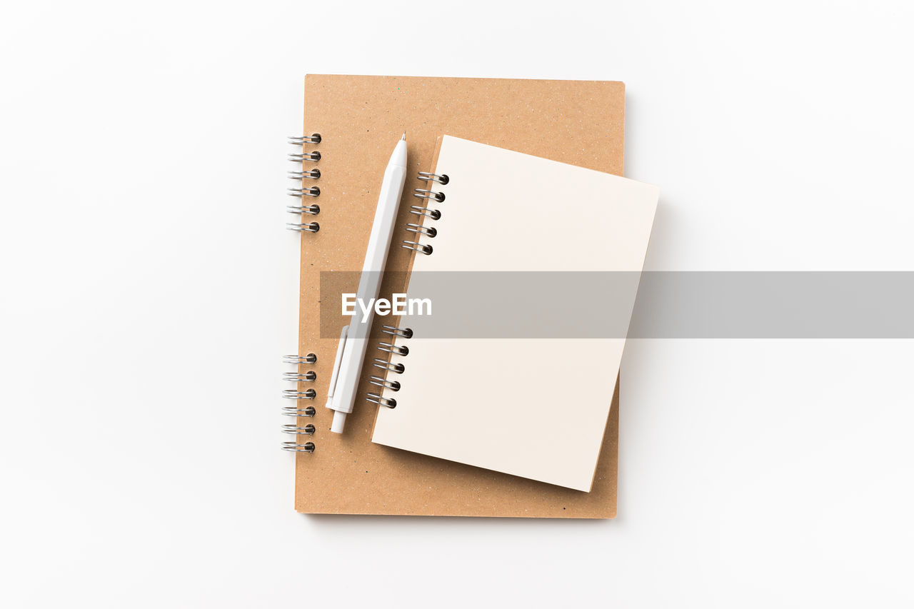 Directly above shot of spiral notebooks against white background