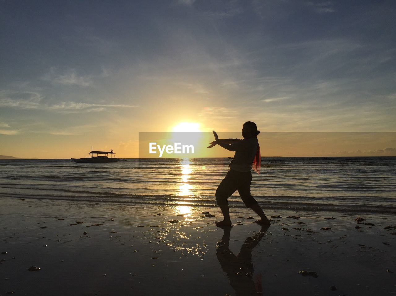 Optical illusion of man holding sun at beach during sunset