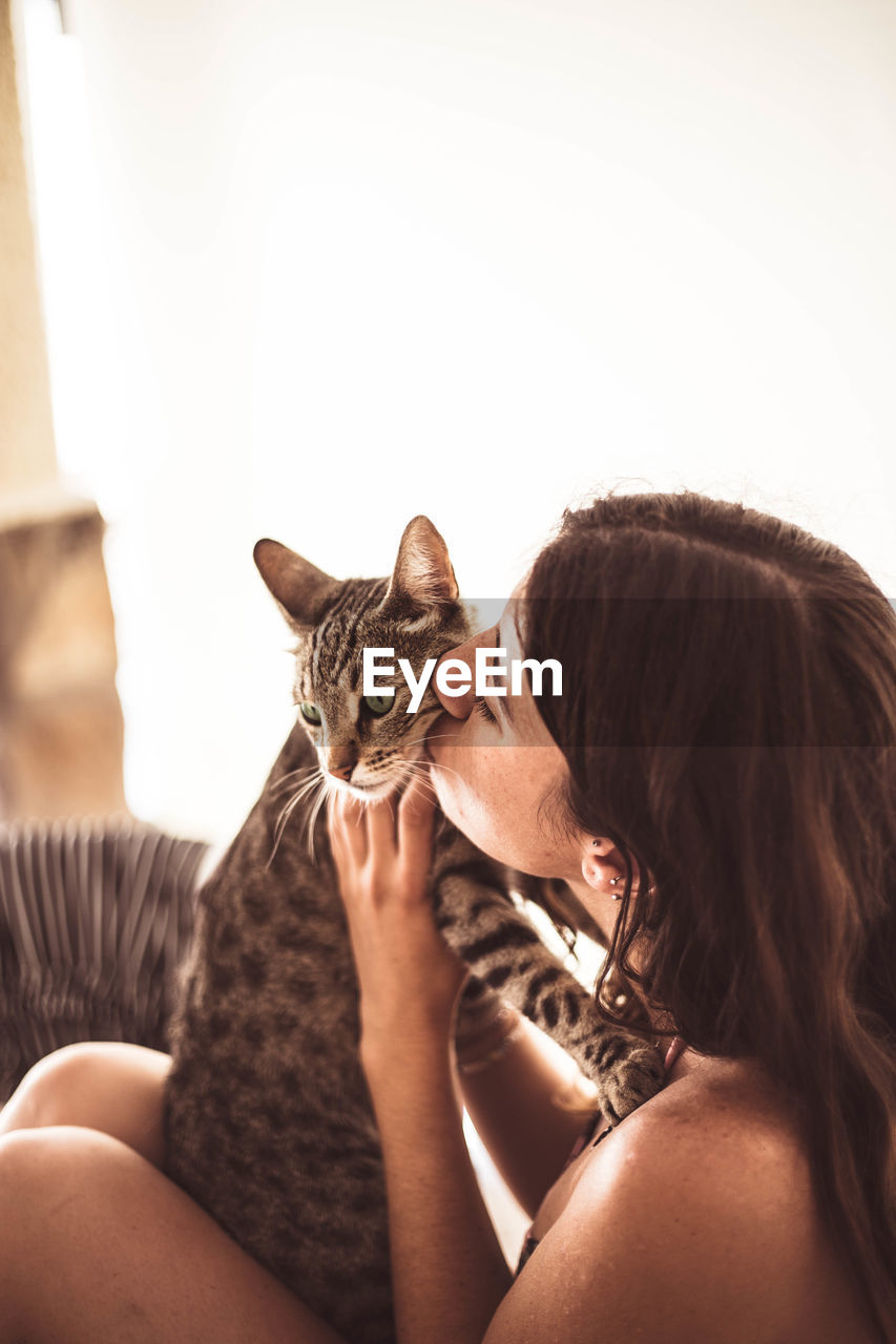 Woman kissing cat at home